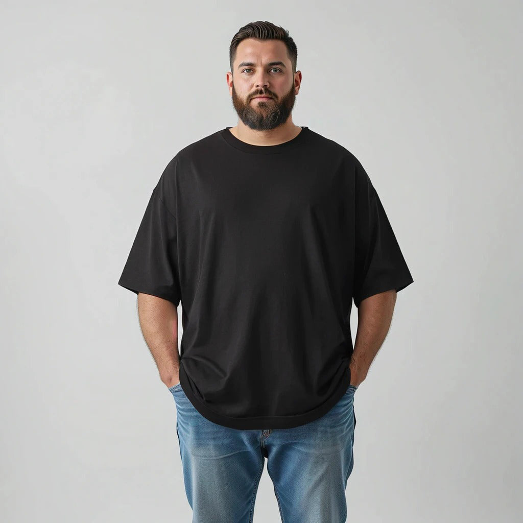 Man wearing a black t-shirt and blue jeans against a gray background