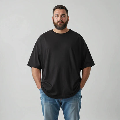 Man wearing a black t-shirt and blue jeans against a gray background