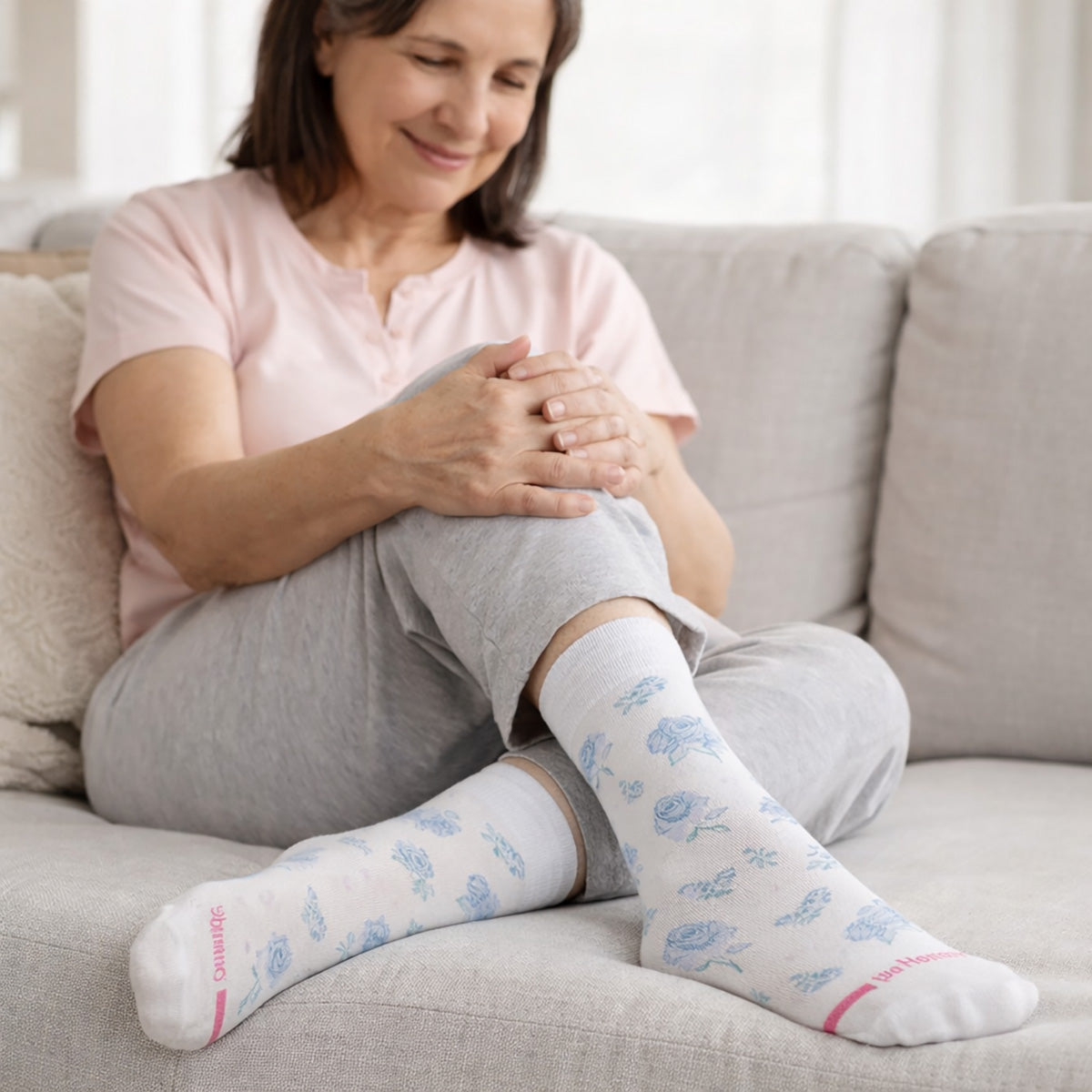 Woman sitting on a couch wearing white dr motion diabetic crew socks with blue patterns.